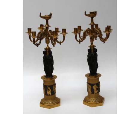 A fine pair of French Empire ormolu and blued bronze table candlesticks. Each with flaming urn sconce above six acanthus scro