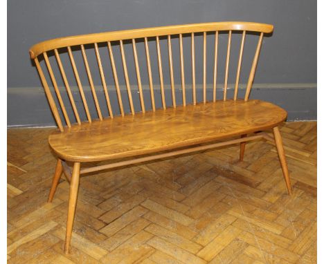 An Ercol blond elm love seat, with stick back, twin saddle seat, raised on splayed legs, 113cm wide