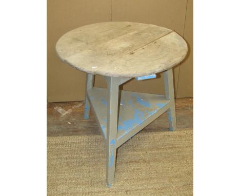 An antique cricket table with under tier, the painted pine base supporting an elm plank top, 75cm high x 75cm diameter