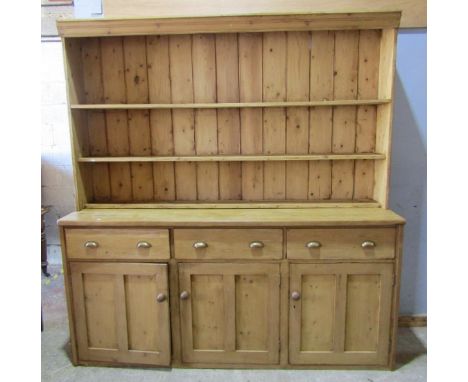 A substantial 19th century stripped and waxed pine kitchen dresser, the base with three panelled doors and three drawers, the