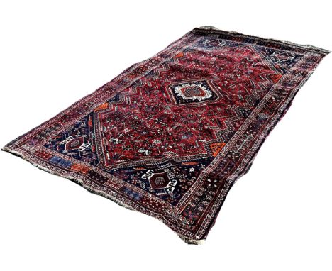 A Persian Carpet with a central radiating medallion with a field of stylised flowers on a red ground, 260cm x 160cm