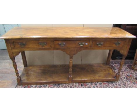 A Georgian style pot board dresser base principally in elm, enclosing three frieze drawers on turned supports, 85cm high x 17