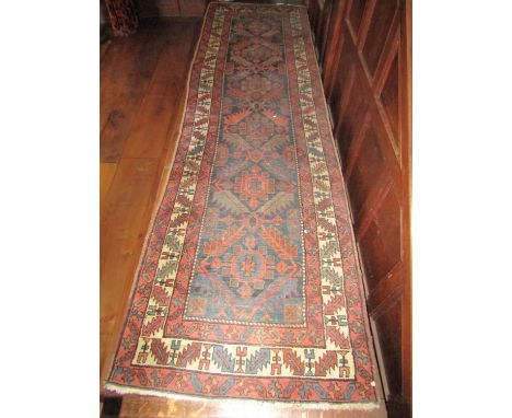 An old eastern wool runner with six medallion centre upon an ink coloured ground, within triple alternating borders with repe