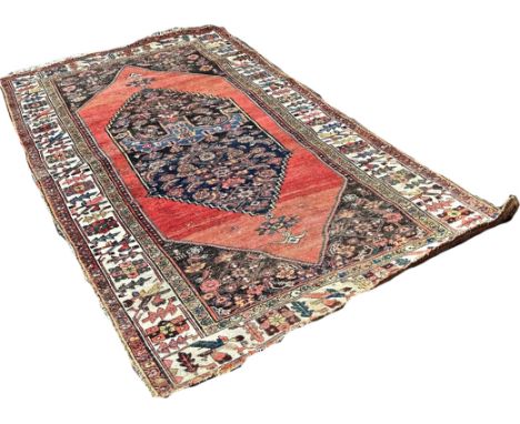 An old Bidjar carpet with an elongated stepped medallion on a red ground and floral borders, 220cm x 140cm approximately