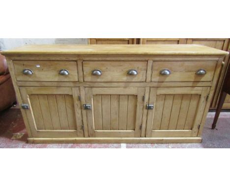 A 19th century stripped and waxed pine dresser fitted with three frieze drawers with iron work cup handles and three panelled