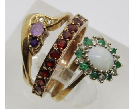 Three 9ct gem set dress rings; an opal, emerald and diamond cluster example, size L/M, a garnet half hoop example and an amet