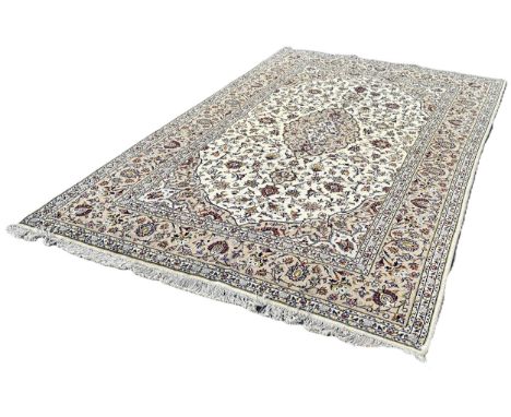 A Central Persian Kashan carpet with an all over floral pattern on a cream and beige ground, 298cm x 200cm approximately