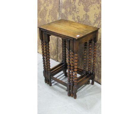 A nest of three graduated 1920's oak occasional  tables on bobbin supports, the outer table 56 cm high x 42 cm x 31 cm, toget