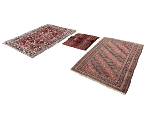 An old Afghan rug with an all over red and black triangular pattern, a camel saddle bag, and a Persian style wall hanging wit