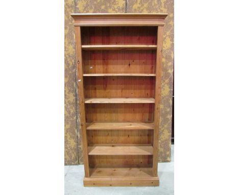 A stripped pine floorstanding open bookcase with four adjustable shelves set on a moulded plinth 197 cm high x 94 cm wide x 2