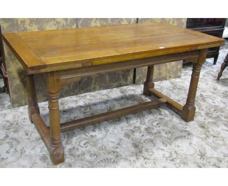 A good quality old English style oak drawer leaf refectory table raised on turned gun barrel supports united by a central str