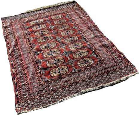 An Afghan Turkoman carpet with rows of elephant foot medallions on a faded red ground, 160cm x 120cm