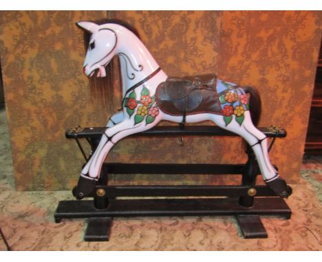 A traditional style rocking horse with painted finish and trailing foliate detail mounted on an ebonised stretcher/supports, 