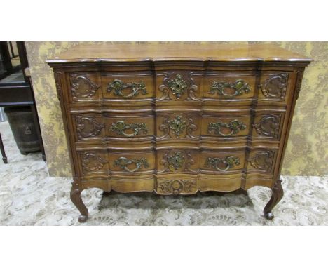 A walnut commode, the serpentine front fitted with three long drawers with carved scrolling acanthus detail and cast brass ha