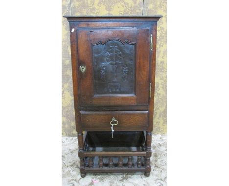 An early 19th century oak side cupboard enclosed by a panelled doors over a frieze drawer with gallery below, the door enclos