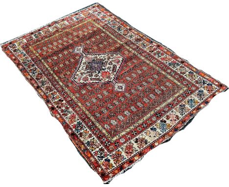 A worn Persian rug with an extended lozenge medallion on a brick red field 120 x 170cm 