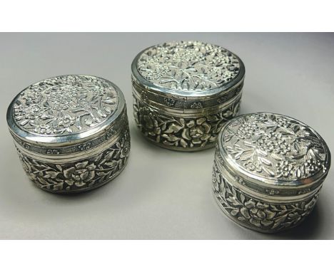 Three graduated Thai silver Betel boxes, all richly decorated with flowers, hallmarks to base, 6.5cm, 6cm and 5cm approximate