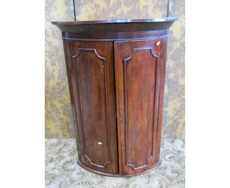 19th century mahogany bow fronted hanging corner cupboard, enclosed by a pair of moulded panelled doors, 109cm high x 73cm x 