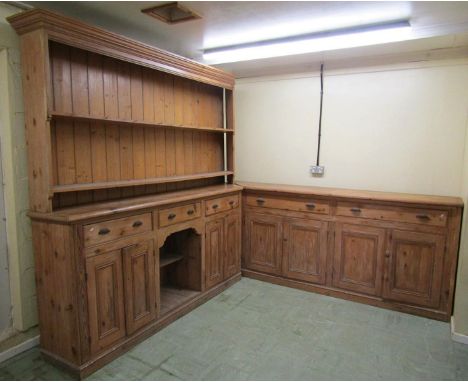 An extensive English country house corner dresser, L shaped in two parts, incorporating a series of panelled doors and drawer