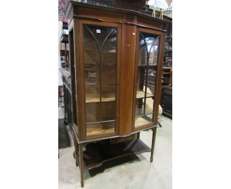 An Edwardian mahogany freestanding display cabinet, the central bow front flanked by glazed panelled doors and inlaid detail,