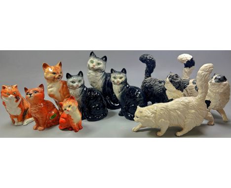 A collection of ceramic cats in various poses by Beswick and Royal Doulton together with two 'Monk' shaped whiskey decanters 
