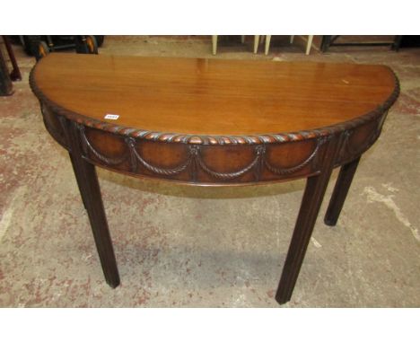 A 19th century mahogany demi lune side table with carved swag and gadrooned detail on moulded supports