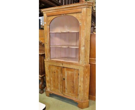 A Georgian stripped pine two sectional freestanding corner cupboard partially enclosed  by a pair of panelled doors beneath o