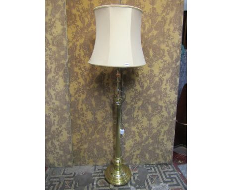 A polished cast brass coated telescopic standard lamp with reeded stem and stepped disc shaped base with lions paw feet 