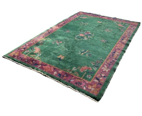 A Chinese design carpet with sprays of flowers on an ever green ground and a purple border, 275cm x 185cm approximately