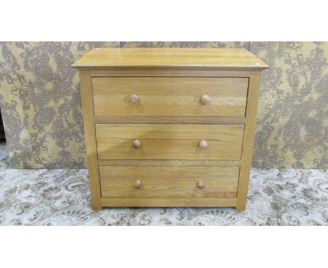 A contemporary light oak bedroom chest of three long drawers with turned tapered handles, 72 cm hi8gh x 80 cm x 44 cm