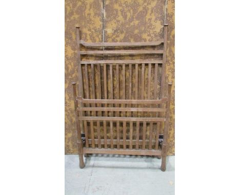 An Arts &amp; Crafts light oak single bedstead with open vertical and horizontal slats raised on simple turned tapered suppor