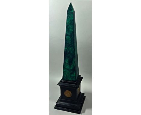 An early 20th Century plaster obelisk with green malachite painted finish on a black plinth decorated with four gold classica