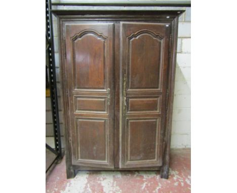 An 18th century oak armoire enclosed by a pair of full length fielded panelled doors within a panelled frame beneath a simple