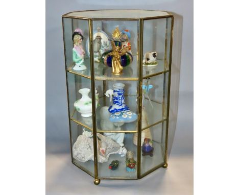 A three tier octagonal display case, with a ready made display objects including a Murano glass bottle, a glass deer, a clois