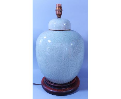 A Chinese celadon green ginger jar with later drilled conversion to a table lamp on a wooden base, 45cm high in total