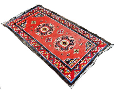 A Tibetan wool carpet with circular floral patterns on an orange ground180cm x 95cm approximately 