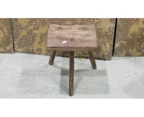 A rustic oak country made milking stool with through jointed splayed supports 34 cm high, the seat 29 cm x 24 cm