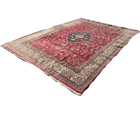 A Persian style country house carpet with a medallion centred in a field of flowers on a red ground, 400cm x 290cm approximat