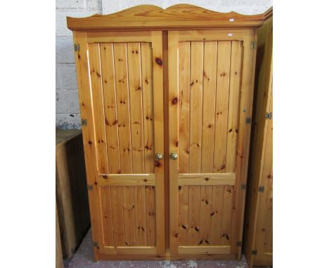 A modern pine wardrobe enclosed by two panelled doors, 195cm high x 120cm x 50cm