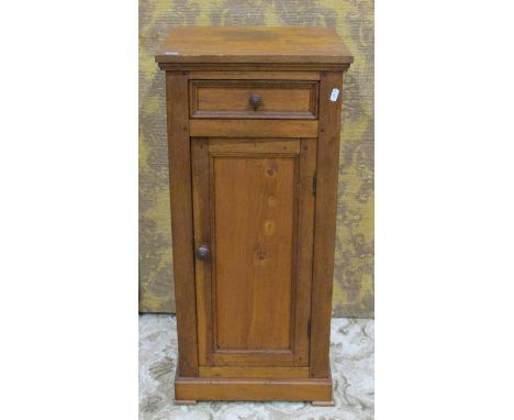 An oak bedside cupboard/lamp table partially enclosed by a rectangular panelled door beneath a frieze drawer 83 cm high x 38 