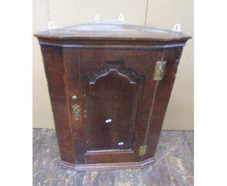 A small 18th century oak hanging corner cupboard with shaped and fielded panelled door 78H x 58W x 33D 