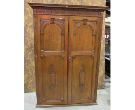 An  old English style oak side cupboard enclosed by a pair of full length panelled doors with arcaded, carved and applied mou