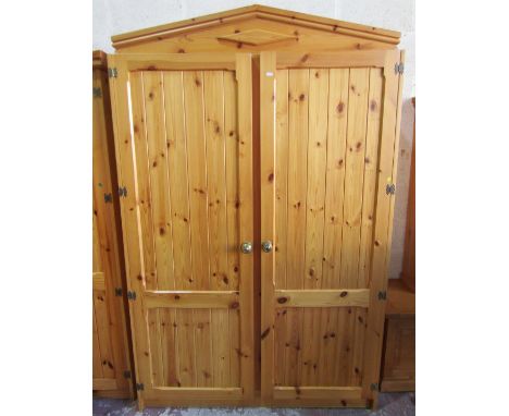 A pine hall cupboard with cornice enclosed by two panelled doors beneath an architectural frieze, 205cm high x 130cm x 56cm