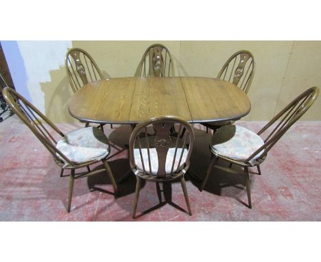 An Ercol dining table and associated chairs with swan splats, the table fully extended 145cm long