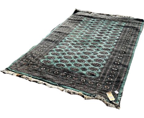 A green Turkoman carpet with a central panel with rows of small medallions, 235cm x 165cm approximately