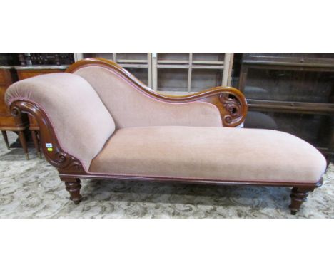 A Victorian mahogany chaise lounge with upholstered seat, back and scrolled head rest within a mahogany show wood frame with 