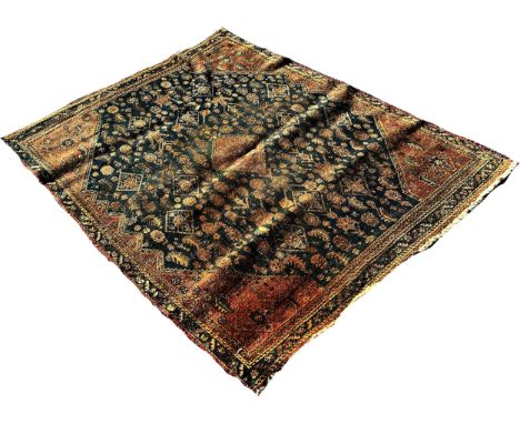 An old Persian carpet, with stylised flowers on a blue ground faded and worn, 160cm x 125cm approximately