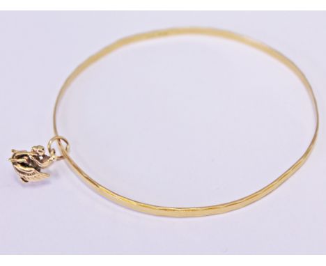 An 18ct gold bangle with 9ct gold charm, gross wt. 7.6g.