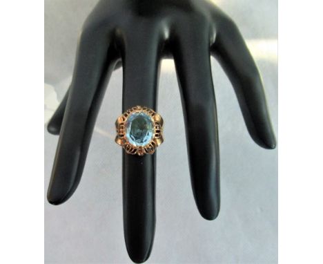 A single stone blue topaz dress ring, the oval cut stone in claw mount above openwork petal design gallery.