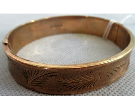 A 9ct gold bangle, the textured slightly curved band engraved with ferns. Condition Report: 15 grams.